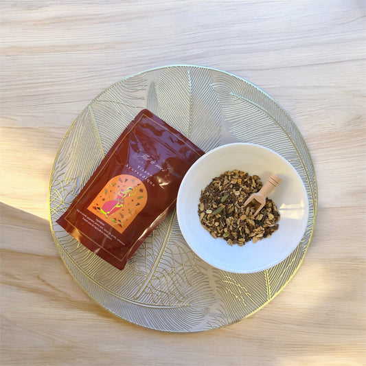 Tisane ayurvédique épicée dans une tasse blanche, cannelle et gingembre visibles